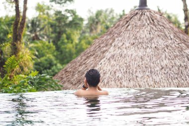 Yüzme havuzunda dinlenen adam. yaz seyahat tatilzevk, Orman görünümüne bakarak.