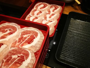 İnsanlar bir restoranda shabu ya da ızgara et yiyor.