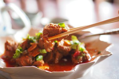 Yemek çubukları üzerinde baharatlı tavada domuz eti