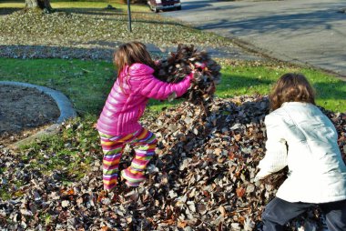 Yaprak yığınında oynayan genç bir kız