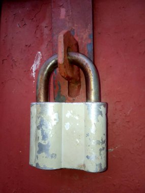 Metal bir kapının üzerinde eski paslı bir kilit.