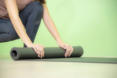 Kadın siyah yoga mat yakın rulo.
