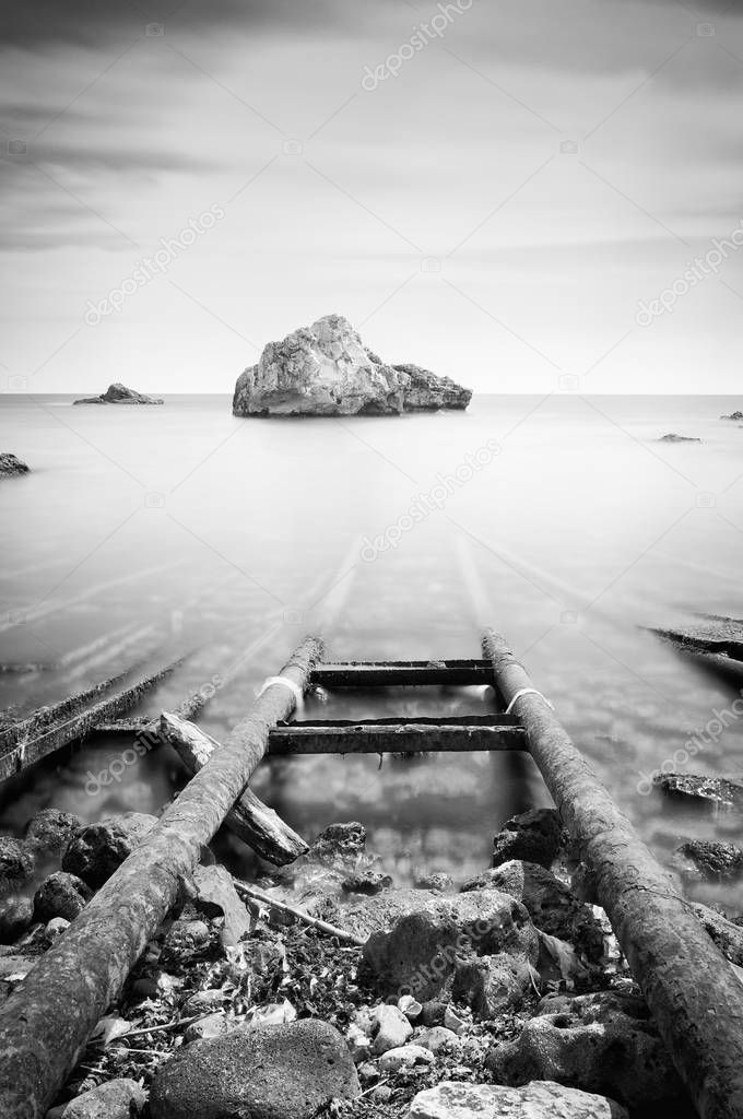 Black and white photo of sea and rocks, long exposure.