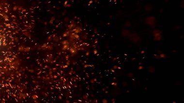 Gece gökyüzündeki büyük ateşten yanan kırmızı kıvılcımlar uçuşuyor. Ateş, ışık ve yaşam teması üzerine çok soyut bir arka plan. Yanan közler siyah arkaplan üzerinde uçan parçacıklar.