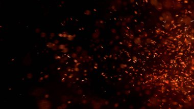 Gece gökyüzündeki büyük ateşten yanan kırmızı kıvılcımlar uçuşuyor. Ateş, ışık ve yaşam teması üzerine çok soyut bir arka plan. Yanan közler siyah arkaplan üzerinde uçan parçacıklar.