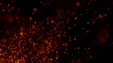 Gece gökyüzündeki büyük ateşten yanan kırmızı kıvılcımlar uçuşuyor. Ateş, ışık ve yaşam teması üzerine çok soyut bir arka plan. Yanan közler siyah arkaplan üzerinde uçan parçacıklar.