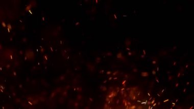 Gece gökyüzündeki büyük ateşten yanan kırmızı kıvılcımlar uçuşuyor. Ateş, ışık ve yaşam teması üzerine çok soyut bir arka plan. Yanan közler siyah arkaplan üzerinde uçan parçacıklar.