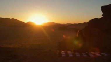 Çöl Wadi Rum Amazing Sunset, Kız halı üzerinde oturuyor ve o dinleniyor. Ürdün'de Kızıl Çöl Wadi Rum Manzara. 
