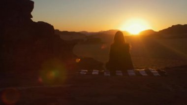 Çöl Wadi Rum Amazing Sunset, Kız halı üzerinde oturuyor ve o dinleniyor. Ürdün'de Kızıl Çöl Wadi Rum Manzara. 
