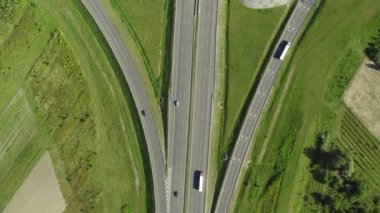 Araba ve kamyon, kavşak, iki katlı yol kavşağı ile otoyol ve üst geçit. Akşam karayolu trafiği üzerinde havadan yüksek drone uçuş. 4k video.