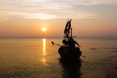 Sabah balığa çıkmak üzere olan bir balıkçı teknesinde iki kişinin silueti..