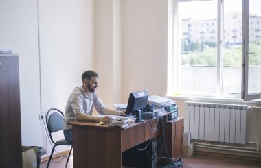 Çekici traşsız genç adam işyerinde ofiste gülümsüyor