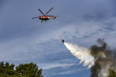 Ukraynalı itfaiye helikopteri ormandaki yangını söndürmek için su boşaltıyor.. 