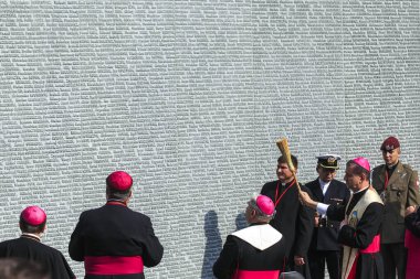 Polonyalıların adlarını taşıyan Anıt Duvarın yanındaki Katolik rahipler, Kyiv yakınlarındaki Bykivnia 'daki Polonya askeri mezarlığındaki Stalinist baskının kurbanları. Ukrayna. Eylül 2012