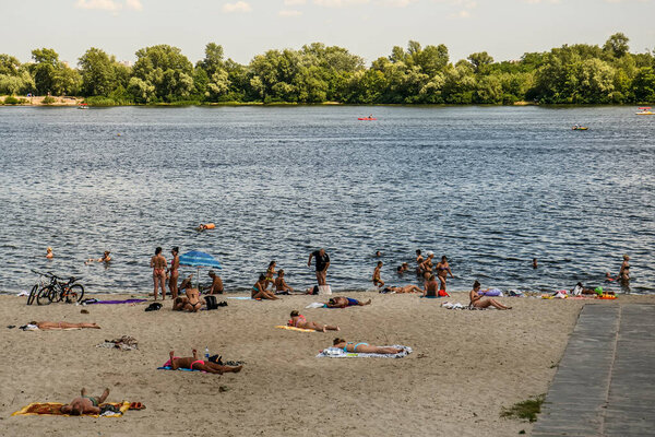 People sunbathe on the sandy beach near Obolon embankment in Obolon district in Kyiv, Ukraine. July 2020. High quality photo