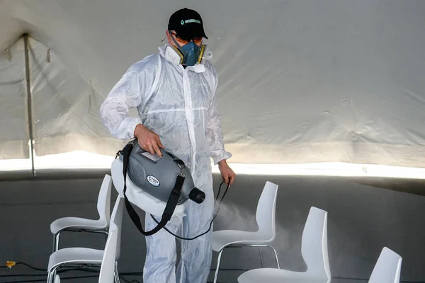 Працівник охорони здоров'я, одягнений в захисне місце для дезінфекції громадської події через спалах коронавірусної хвороби COVID 19 — стокове фото
