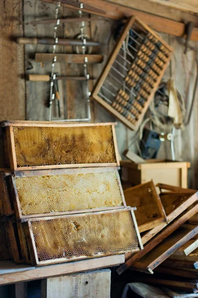 Wooden frames with honeycomb and different tools in the barn