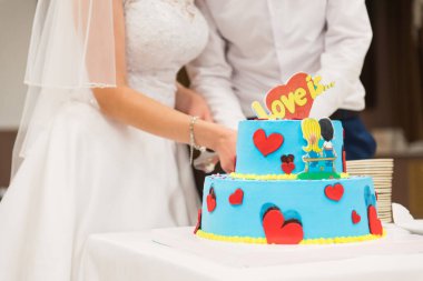 PERM, RUSSIA - 27 JUL 2018: Yeni evliler mavi düğün pastasını resimlerle kestiler 