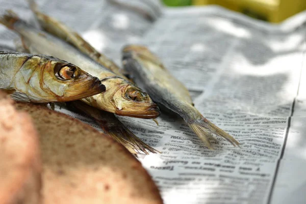 Golden smoked fish and bread on newspaper.