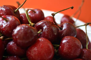 Turuncu arka plan üzerinde ahşap bir masa üzerinde taze kiraz Beyaz kase.