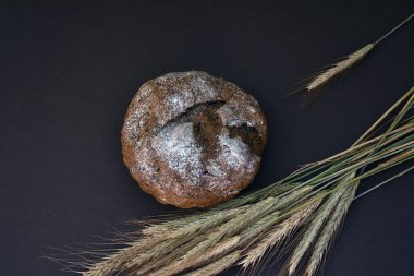 Somun ekmek ve koyu bir arka plan üzerinde buğday kulakları, üst görünümü.