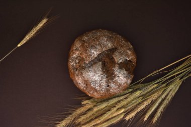 Somun ekmek ve koyu bir arka plan üzerinde buğday kulakları, üst görünümü.