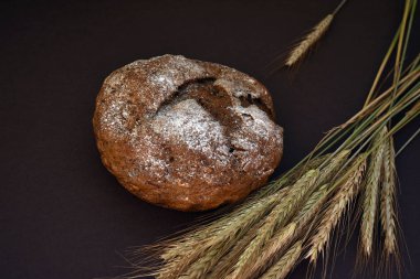 Koyu bir arka plan üzerinde ekmek ve buğday kulakları somun. Closeup