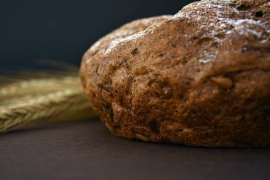 Koyu bir arka plan üzerinde ekmek ve buğday kulakları somun. Closeup