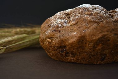 Koyu bir arka plan üzerinde ekmek ve buğday kulakları somun. Closeup