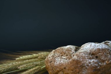 Koyu bir arka plan üzerinde ekmek ve buğday kulakları somun. Closeup