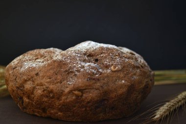 Koyu bir arka plan üzerinde ekmek ve buğday kulakları somun. Closeup