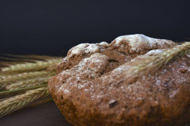 Koyu bir arka plan üzerinde ekmek ve buğday kulakları somun. Closeup