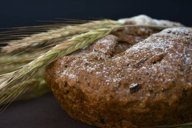 Koyu bir arka plan üzerinde ekmek ve buğday kulakları somun. Closeup