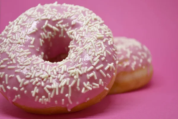 Donuts mit Sahnehäubchen auf pastellrosa Hintergrund. Süße Donuts. — Stockfoto