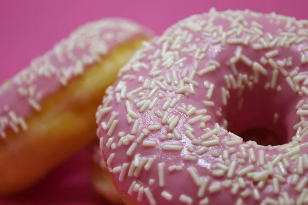 Пончики з глазур'ю на пастельно-рожевому тлі. Солодкі пончики . — стокове фото