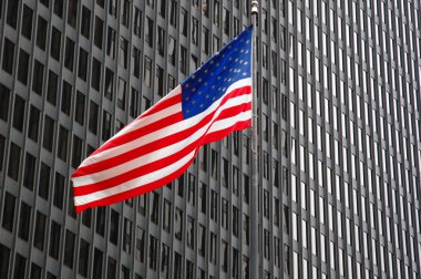 Arka planda gökdelen pencereleri ile Amerikan bayrağı.