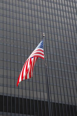 Arka planda gökdelen pencereleri ile Amerikan bayrağı.