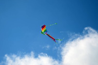 Gökkuşağı renkli uçurtma gökyüzünde uçuyor.
