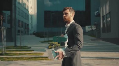 Çekici bir ofis çalışanı bir kutu kişisel eşyası ile yürürken Coronavirus krizi yüzünden işten atıldı. İşsiz iş dünyası ağır çekim iş ekonomisi.