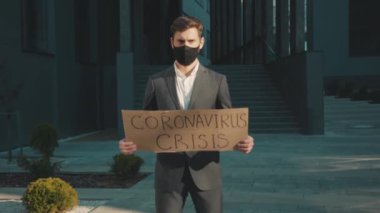 Çekici bir adam, elinde Coronavirus krizi ile karton poster tutan maskeli işsiz profesyonel finans ekonomisini gösteren mesajlı bir adam.
