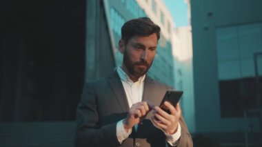 Şehir merkezinde yakışıklı mutlu bir adam duruyor. Telefon mesajı atıyor, gülümsüyor, gülümsüyor, iletişim kuruyor. Gün ışığında başarı yavaş çekim.