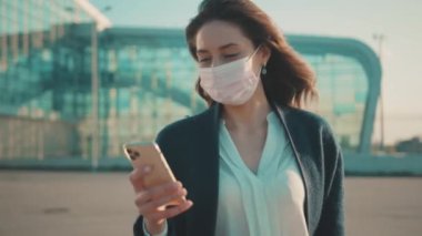 Ofisteki neşeli esmer kadın, sosyal medyayı akıllı telefondan kontrol ediyor. Güneşli bir gün. Sağlık hizmetleri, salgın.