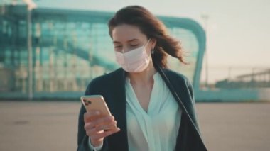 Neşeli genç iş kadını akıllı telefondan salgın haberlerini kontrol ediyor. Karantinanın sona ermesini kutlayan tıbbi maskeyi çıkarıyor. Coronavirus kazandı. Sağlık hizmetleri. Yeni hayat.