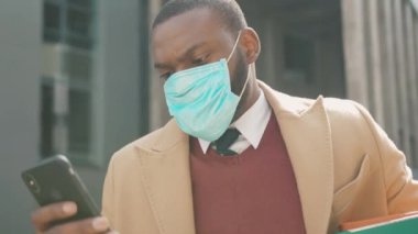 Yüzünüzü kapatın Afrikalı Amerikalı adam telefon giyim maskesini kişisel eşyalarla dolu olarak kullanıyor. Coronavirus krizi yüzünden işten çıkarıldı. İşsizlik ekonomisi yavaş çekim.