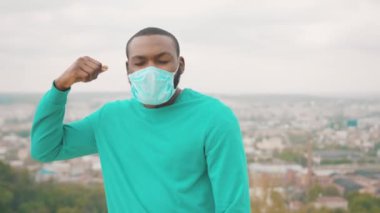 Yüzüne maske takan mutlu zenci iş adamı portresi tatmin ve rahatlamış hissediyor. Dağ tepesi. Şehir manzarası. Karantina sona erdi. Coronavirus. Salgın.