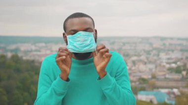 Açık hava portresi siyah sakallı adam, pandemik karantina sırasında sağlık için yüz savaşında koruyucu mavi maske takıyor. Dağ tepesi. Sosyal uzaklık. Covid 19.