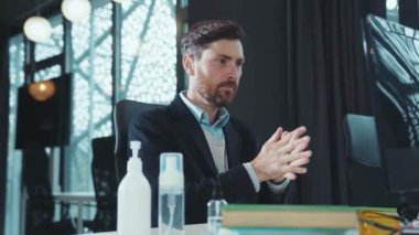 Yakışıklı adam dizüstü bilgisayarı karantinaya almadan önce antiseptikle ellerini dezenfekte ediyor. Bilgisayar hijyenik ofis çalışanı salgın hijyenik dezenfeksiyon salgını ağır çekimde.