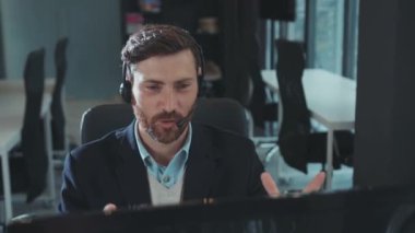 Face happy man kulaklığı iş için kullanıyor bilgisayarla konuşuyor modern ofis programcısı gülümsüyor monitörde çalışan başarılı iş adamına bakıyor yavaş çekim