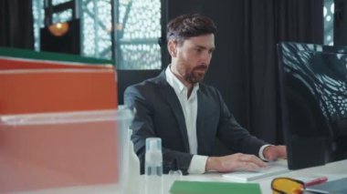 Genç ofis çalışanı bilgisayar kullanıyor. Masasındaki ofis eşyalarıyla birlikte kutuya bakıyor. Coronavirus krizi yüzünden kovulmuş hissediyor.