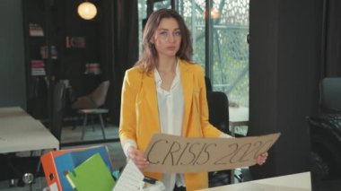 NEW YORK - 28 Mart 2020: Genç ve güzel bir iş kadını, şirket odasının içinde gizli bir karton pankart göstererek işi bırakıyor. Küresel ekonomik kriz 2020. İşsizlik Kurumu.